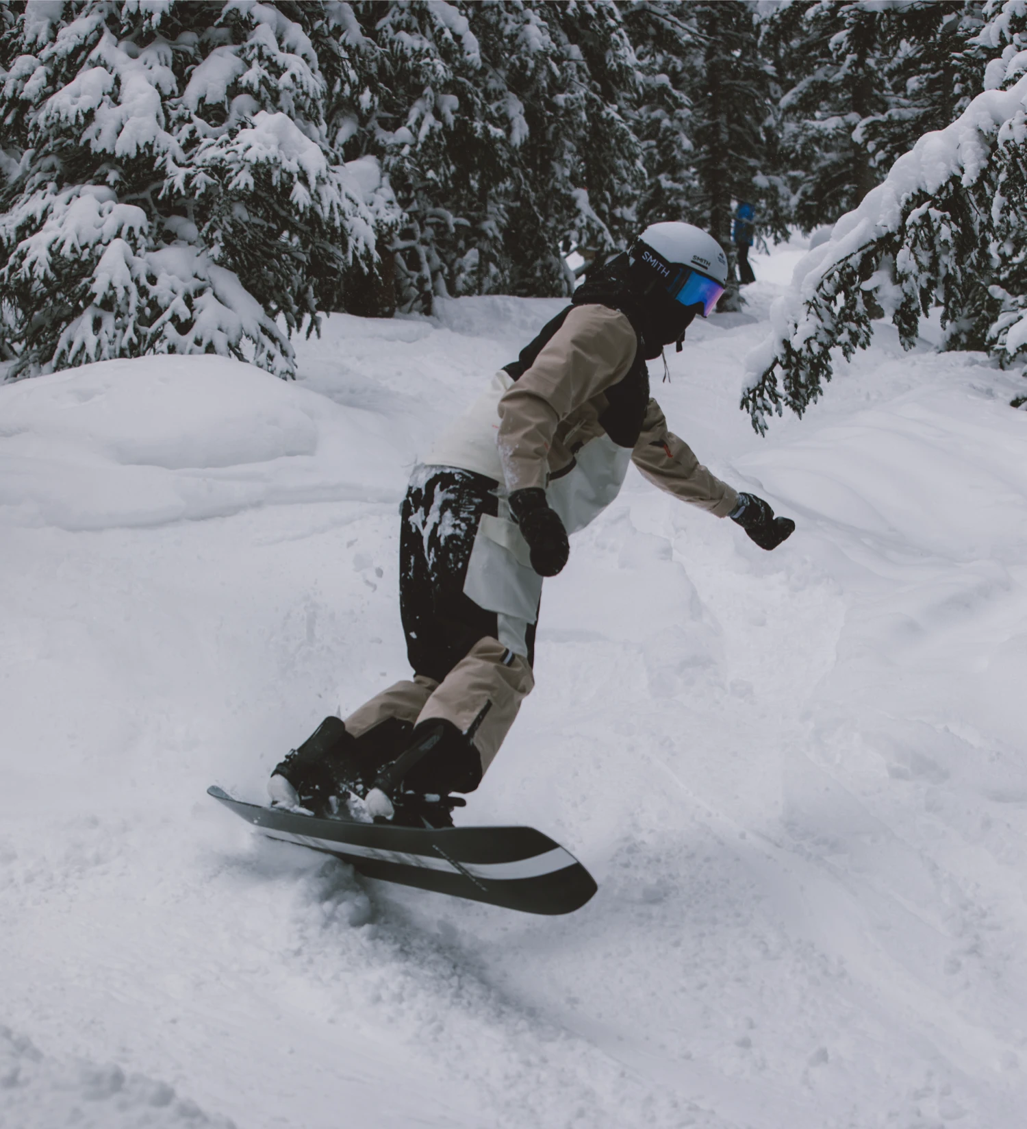 Snowboarder carving through fresh powder in a snowy forest, wearing winter outerwear and helmet.